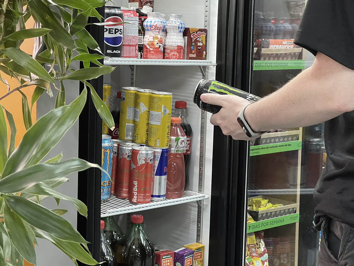 Sala de escritório com duas pessoas em primeiro plano, um homem e uma mulher e duas pessoas em plano de fundo. A mulher em primeiro plano está apontando para o homem algumas escritas tela do computador